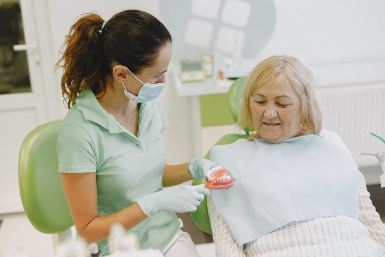 Dentist showing patient how to brush dentures.