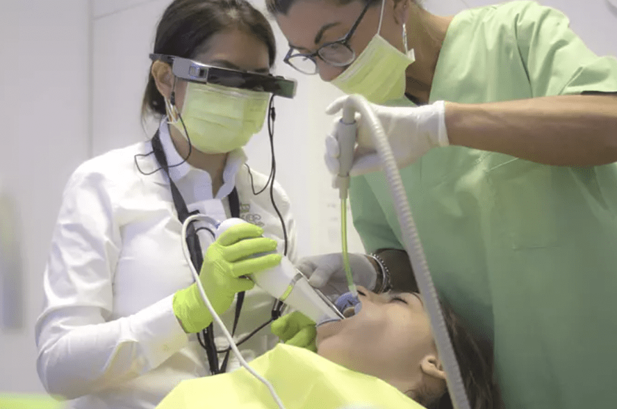 two dental professionals standing over patient