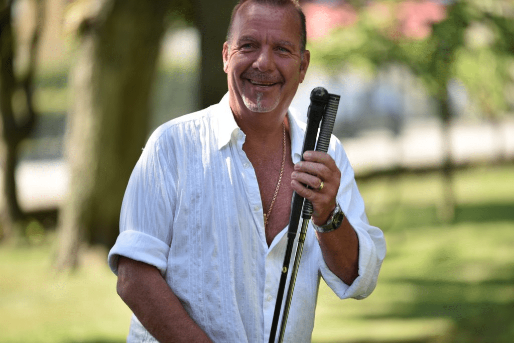 Man in white holding two golf clubs